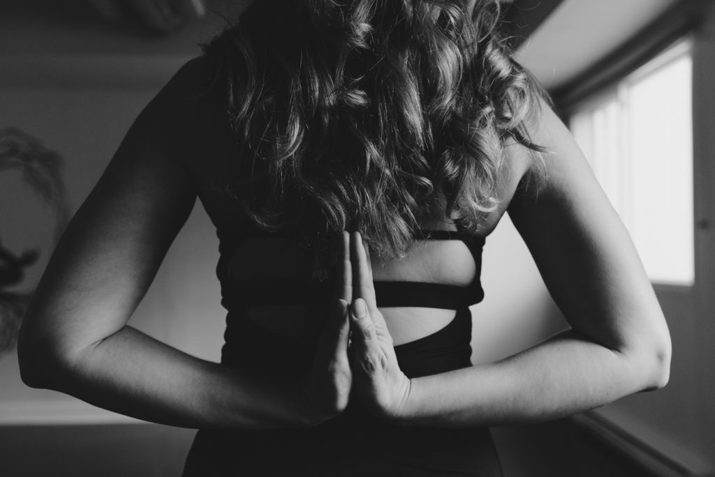 yoga teacher with hands in reverse prayer