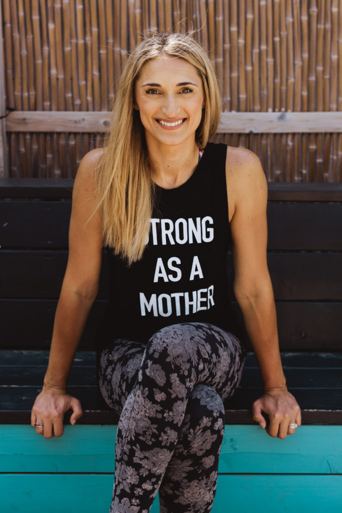 registered nurse sitting on a bench wearing shirt that says "strong as a mother"