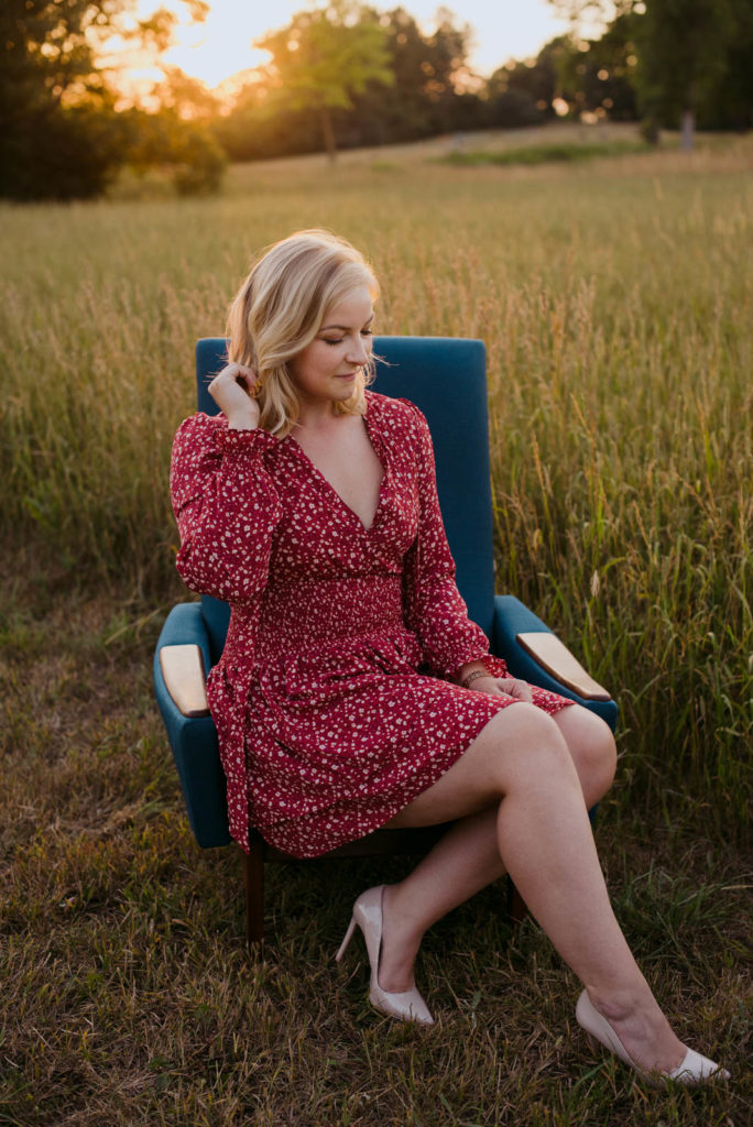 girl in a red dress sitting in a blue chair at sunset