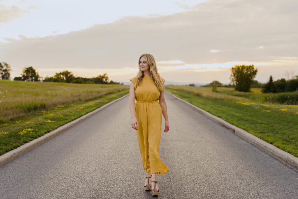 Stephanie Karlovits female entrepreneur wearing yellow walking down a road at sunset