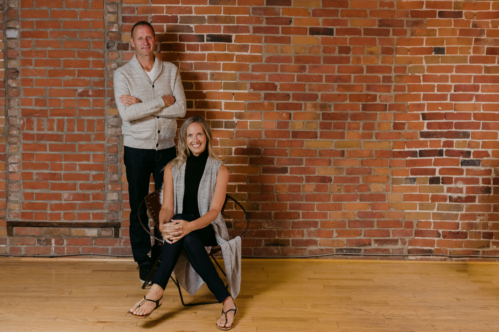 man and wife business owners standing against brick wall