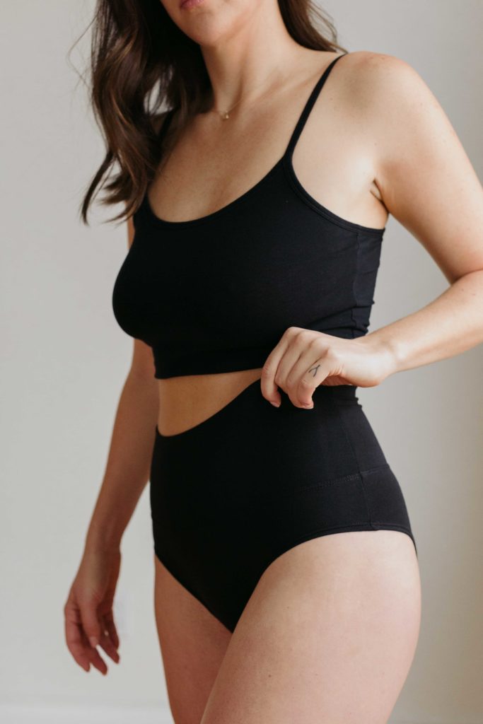 lifestyle photo of lingerie model pulling up waistband of black underwear