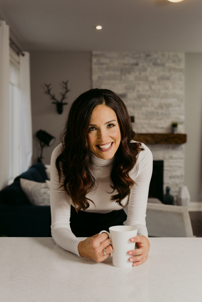business woman laughing at the kitchen counter with a cup of coffee