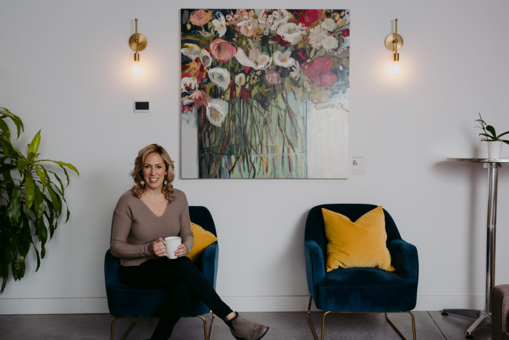 Sarah Hunter real estate agent smiling at the camera sitting in a blue chair