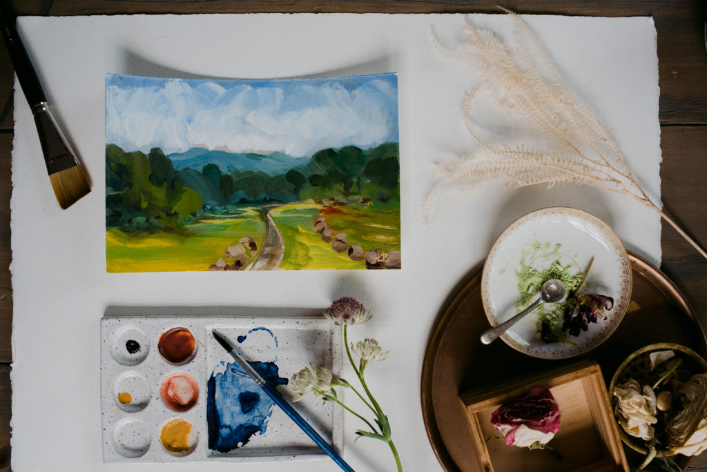 flat lay with landscape painting and paint palette with flowers