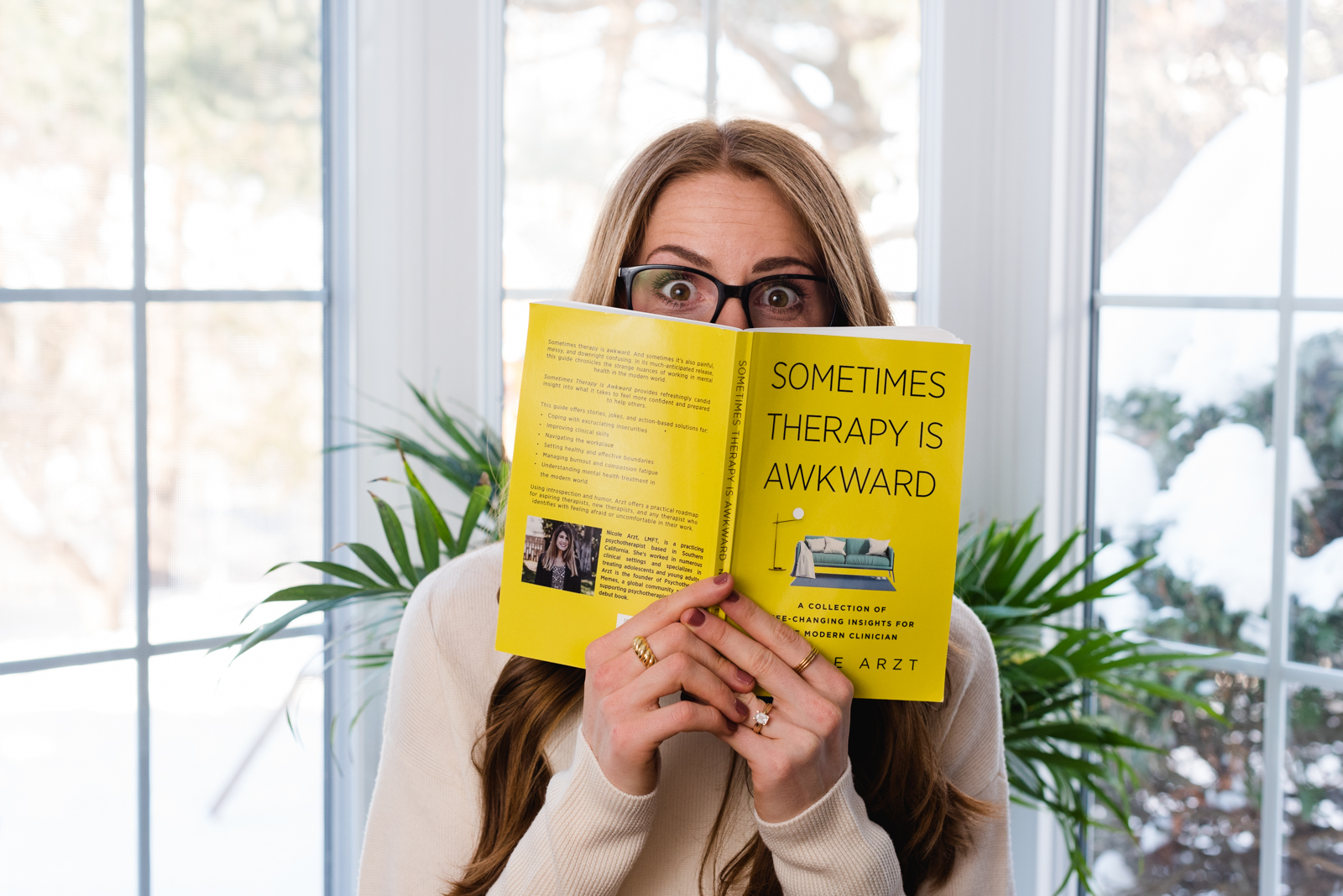 psychotherapist holding book up in front of her face