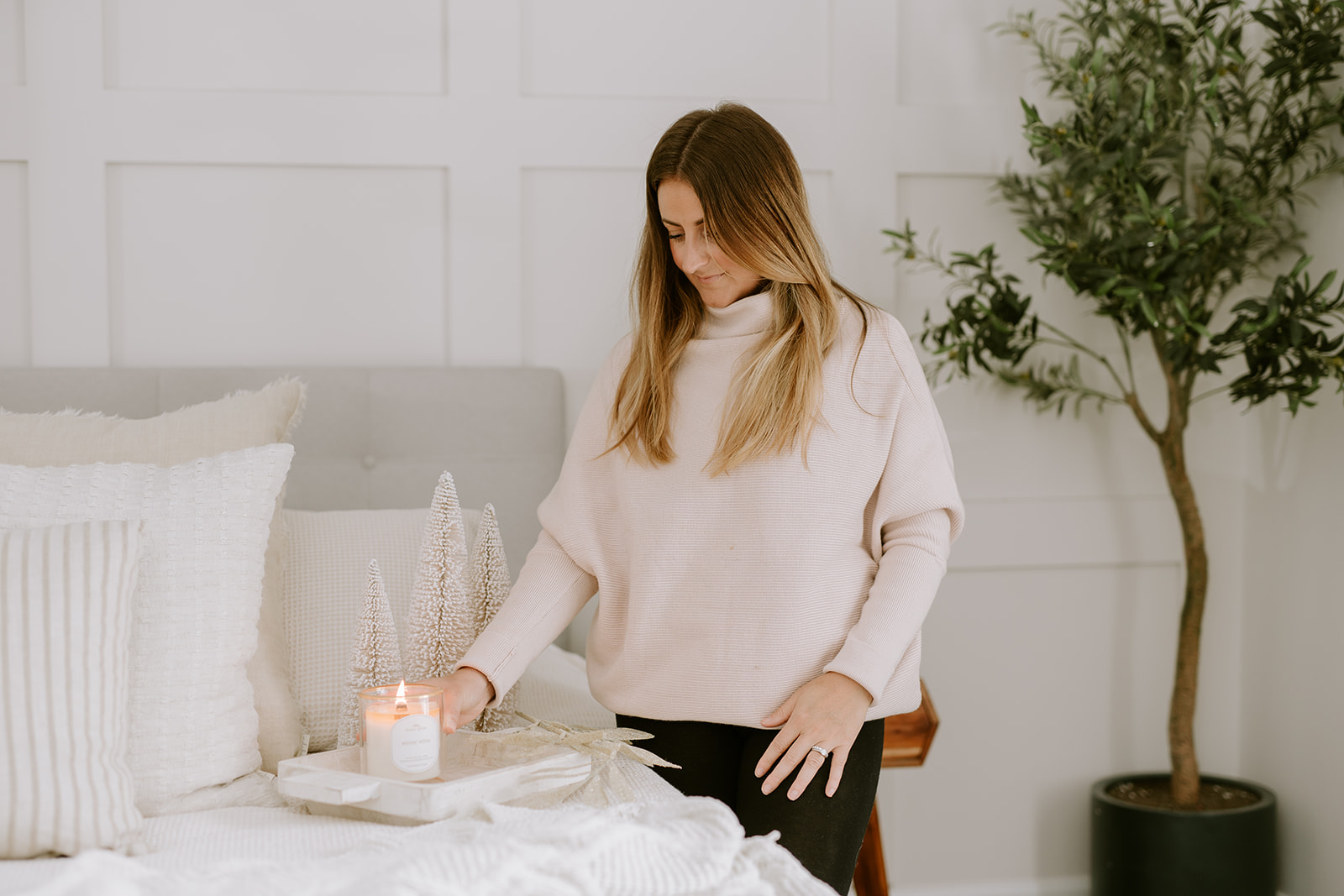 woman placing candle on tray in bedroom